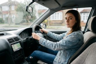 Jeune femme tenant le volant d'une voiture compacte, assise en position de conduite lors de sa première leçon de conduite